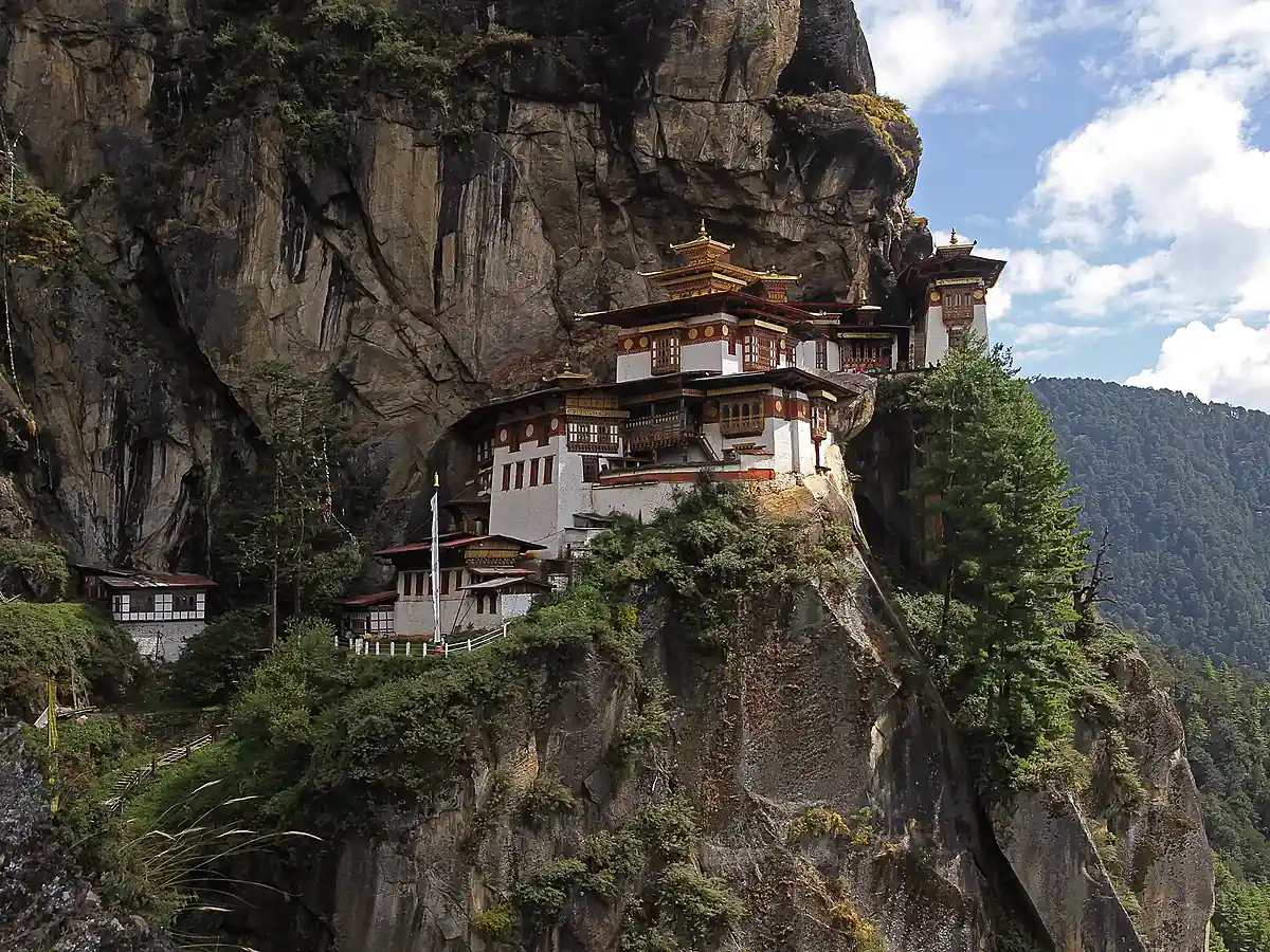 Paro Taktsang clinging to the cliff face above a forested gorge