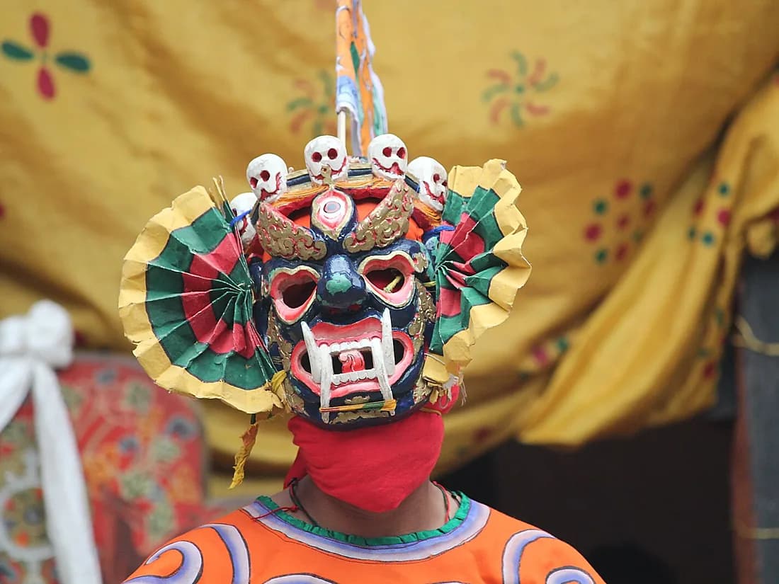 A masked cham dancer in costume at a tshechu festival in Bhutan